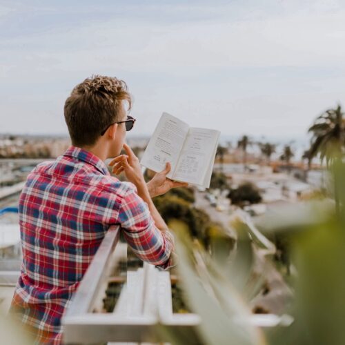man reading book on balcony during daytim