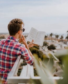 homem lendo livro na varanda durante o dia