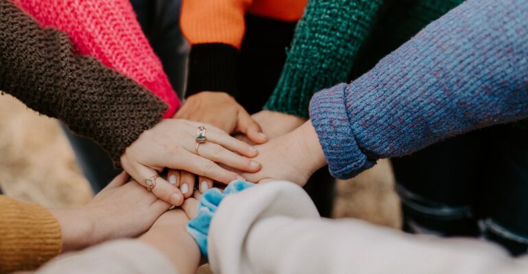 person in red sweater holding babys hand