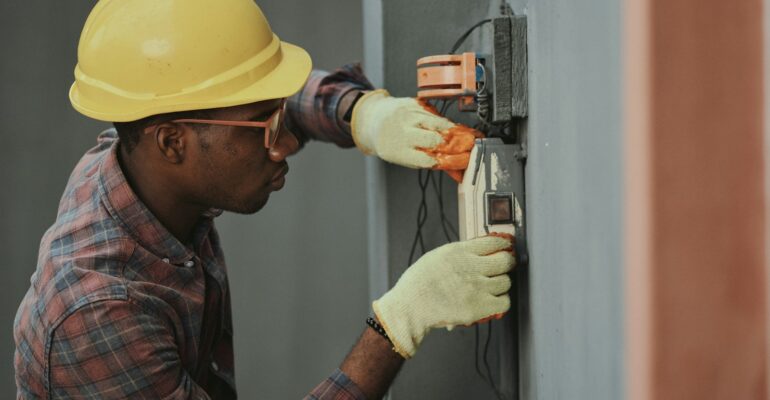 man in brown hat holding black and gray power tool