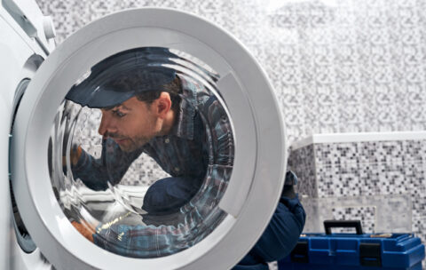 É fácil. Encanador trabalhador verificando máquina de lavar no banheiro
